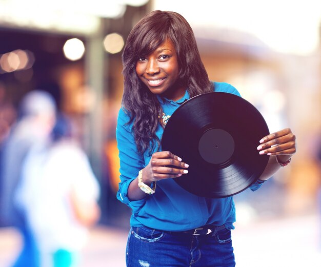 Adolescente sonriente sujetando un vinilo negro