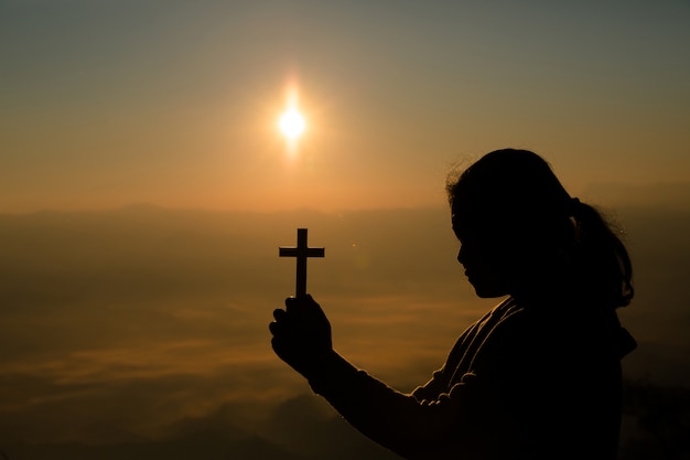 Adolescente sosteniendo la cruz con la oración. Concepto de paz, esperanza, sueños.