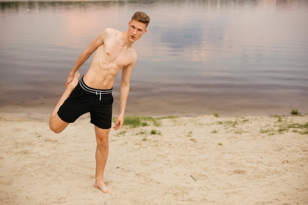 Adolescente de tiro completo haciendo ejercicio en la playa