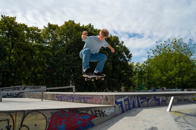 Adolescente de tiro completo haciendo truco en patineta