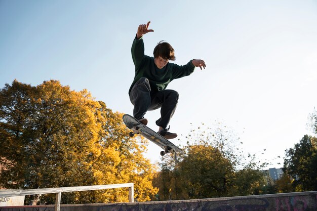 Adolescente de tiro completo haciendo trucos en patineta