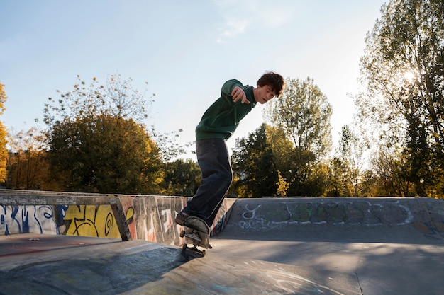 Foto gratuita adolescente de tiro completo con patineta afuera