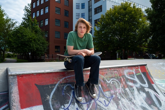 Adolescente de tiro completo sentado con patineta