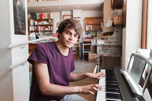 Adolescente tocando el piano y mirando la cámara