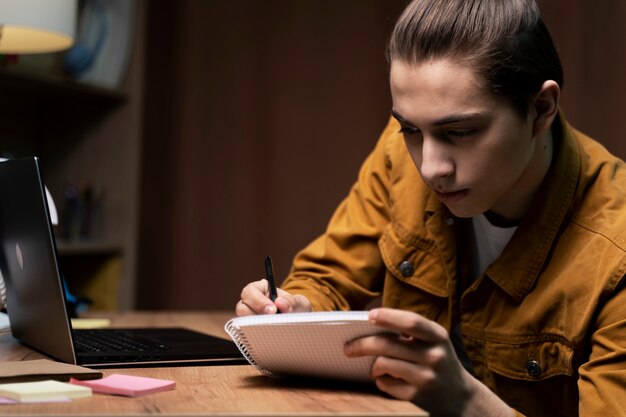 Adolescente tomando notas de la computadora portátil en casa