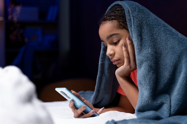 Foto gratuita adolescente usando un teléfono inteligente en casa