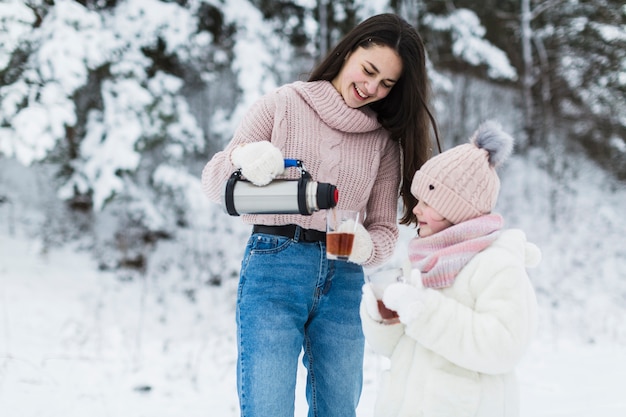 Foto gratuita adolescente vertiendo té para niña