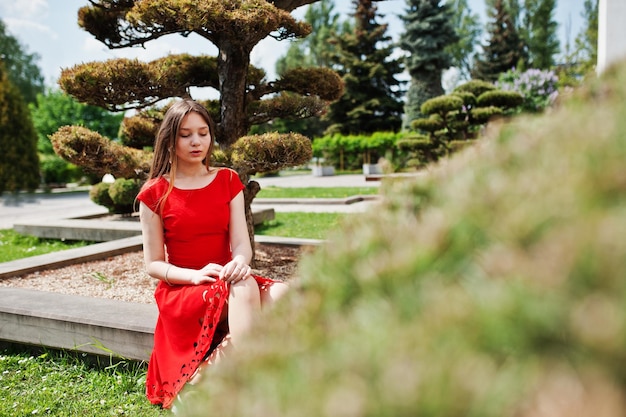 Adolescente en vestido rojo posó al aire libre en un día soleado