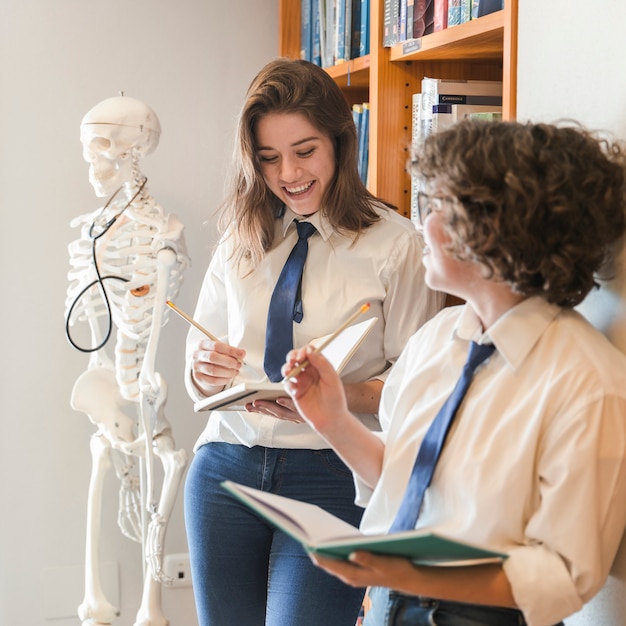 Foto gratuita adolescentes alegres que estudian en la biblioteca