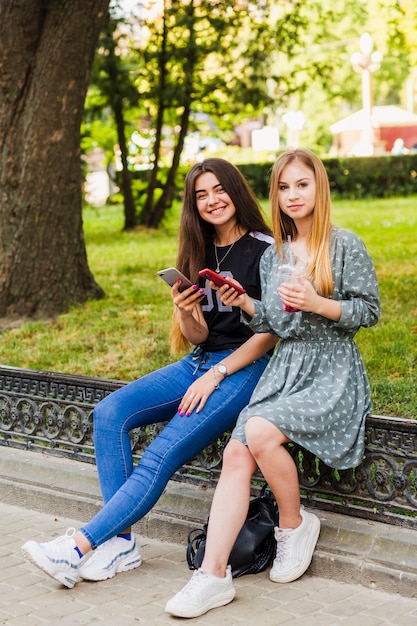 Adolescentes alegres con teléfonos inteligentes y bebidas