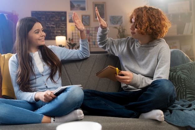 Adolescentes en casa jugando juntos en cuadernos