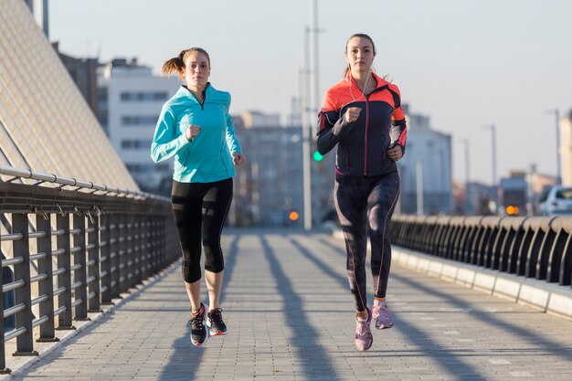 Adolescentes concentradas corriendo con la ciudad de fondo