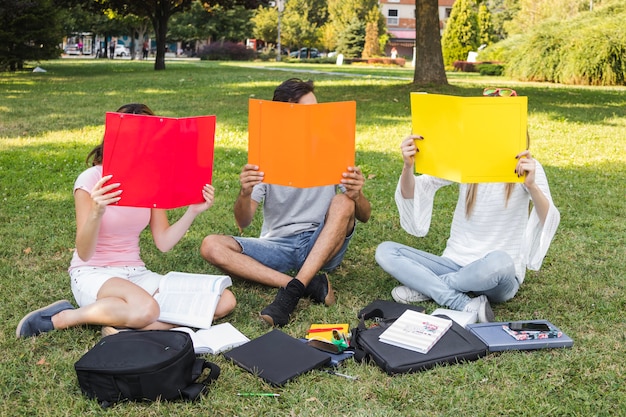 Adolescentes cubriendo caras con carpetas