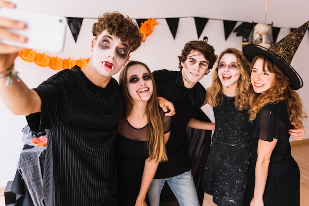 Adolescentes en disfraces de Halloween haciendo selfie