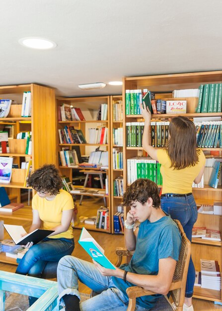 Adolescentes enfocados leyendo cerca de un amigo