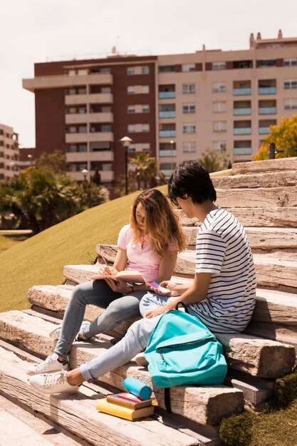 Adolescentes estudiando juntos en las escaleras en la calle