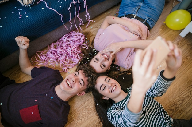 Adolescentes felices tomando una selfie tirado en el piso