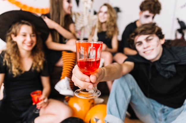 Adolescentes en fiesta de Halloween bebiendo de vasos con sangre pintada