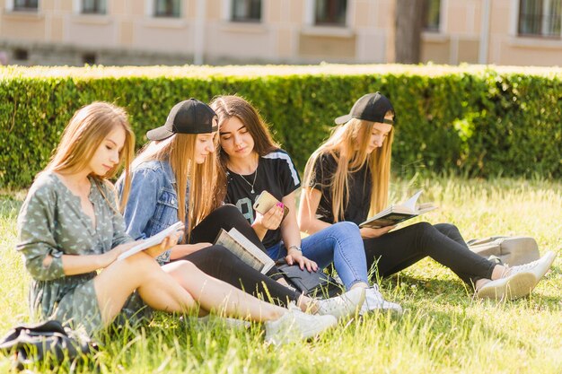 Las adolescentes hablando cerca de amigos de lectura