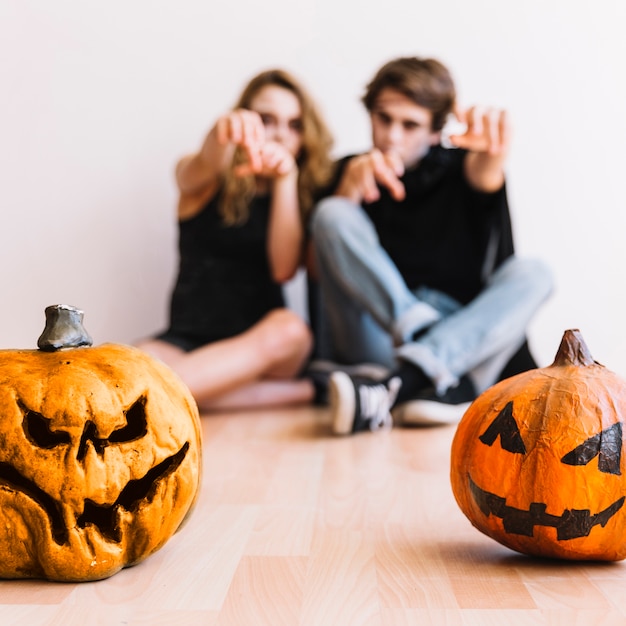 Adolescentes haciendo gestos zombie detrás de calabazas