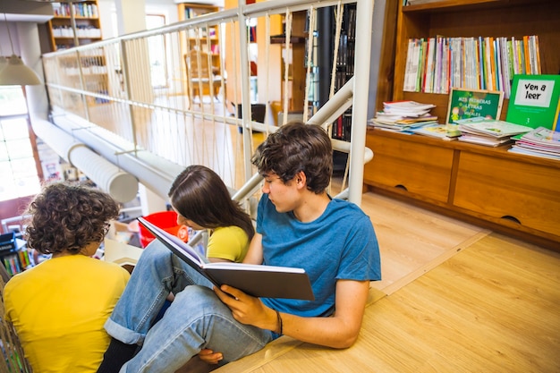 Adolescentes leyendo libro cerca de compañeras de clase