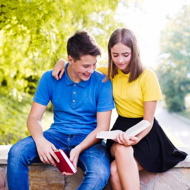 Adolescentes leyendo libros afuera