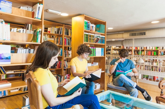 Adolescentes leyendo libros alrededor de la mesa