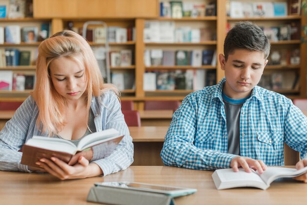 Adolescentes leyendo en la mesa de la biblioteca