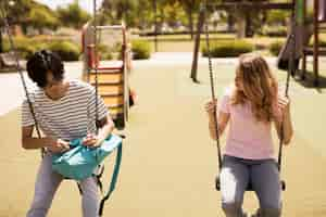 Foto gratuita adolescentes multiétnicos sentados en columpios