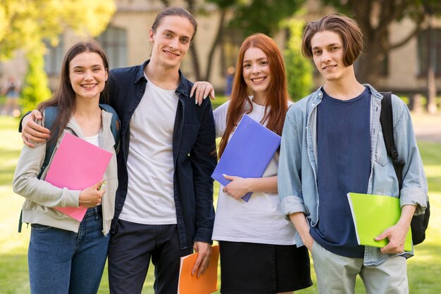 Adolescentes positivos posando juntos en la universidad