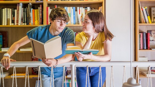 Adolescentes que se comunican mientras leen en la biblioteca
