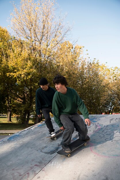 Adolescentes rebeldes de tiro completo en patinetas