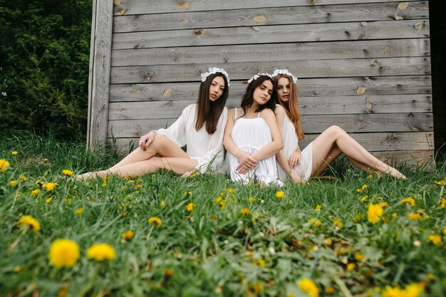 Adolescentes relajadas con coronas florales blancas sentadas en el césped