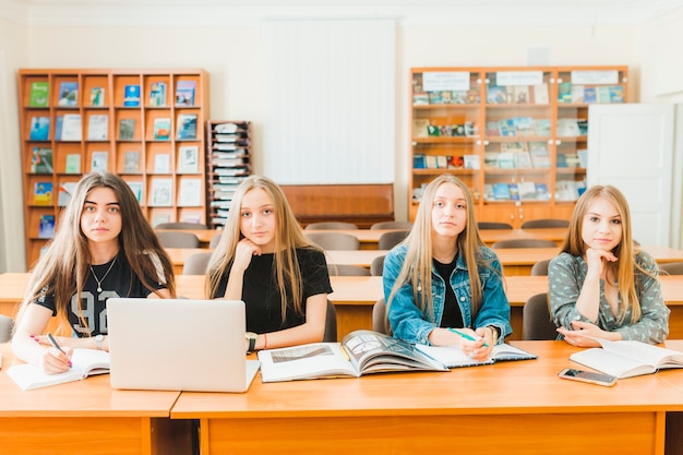 Foto gratuita adolescentes sentados en mesas en el aula