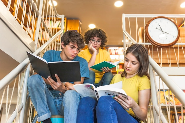 Adolescentes sentados en pasos y estudiando