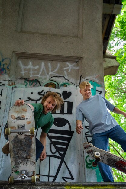 Adolescentes sonrientes de ángulo bajo con patinetas