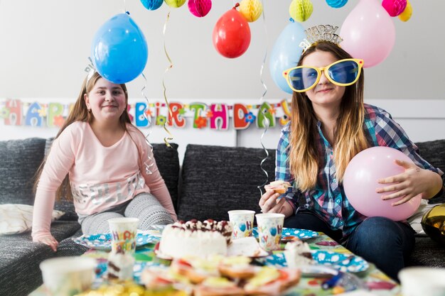 Adolescentes sonrientes comiendo en la fiesta de cumpleaños