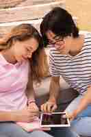 Foto gratuita adolescentes sonrientes navegando por internet en tableta en las escaleras