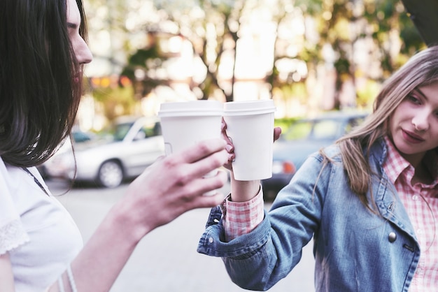 Adolescentes sonrientes con tazas de café en la calle. Bebidas y concepto de amistad.