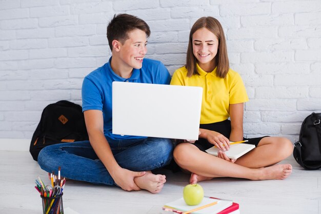 Adolescentes sonrientes usando la computadora portátil