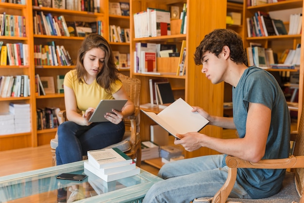 Adolescentes con tableta y libro estudiando