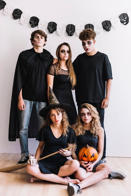 Adolescentes en trajes de Halloween con escoba y calabaza