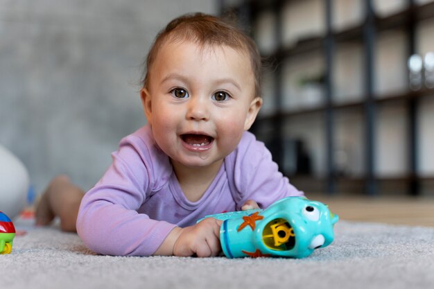 Adorable bebé acostado y jugando en el suelo con juguete