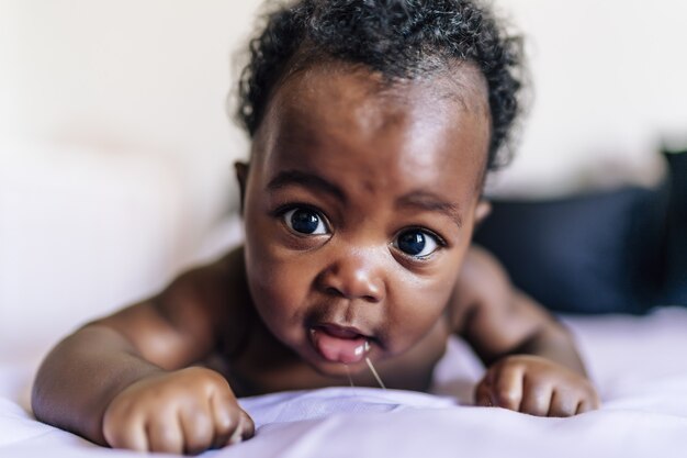 Adorable bebé afroamericano acostado en la cama y sonriendo