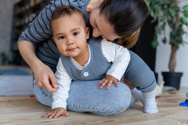 Adorable bebé gateando en el regazo de su madre