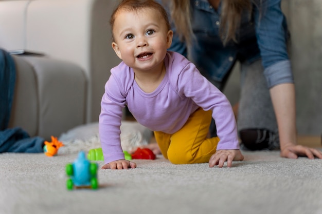 Adorable bebé jugando con juguetes en casa en el suelo