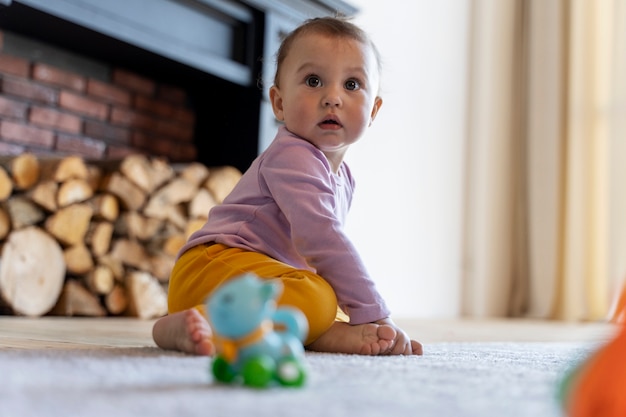Adorable bebé jugando con juguetes en casa en el suelo