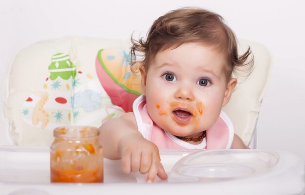 Adorable bebé mujer manchado comiendo su comida favorita