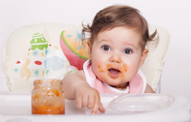 Adorable bebé mujer manchado comiendo su comida favorita
