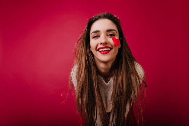 Adorable chica europea con cabello largo que expresa felicidad en el día de san valentín